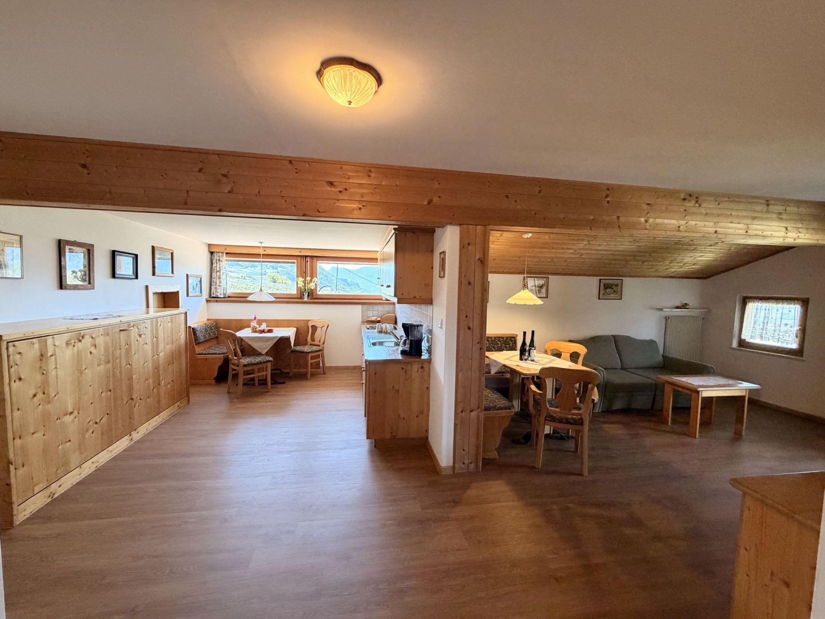 Innenaufnahme einer gemütlichen Ferienwohnung mit offener Küchenzeile, einem Essbereich links und einer Sitzecke mit Sofa rechts im Landhausstil.