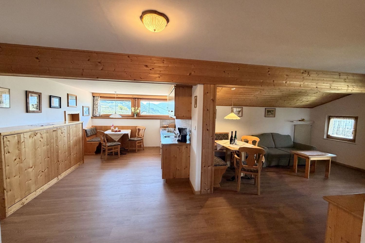 Innenaufnahme einer gemütlichen Ferienwohnung mit offener Küchenzeile, einem Essbereich links und einer Sitzecke mit Sofa rechts im Landhausstil.
