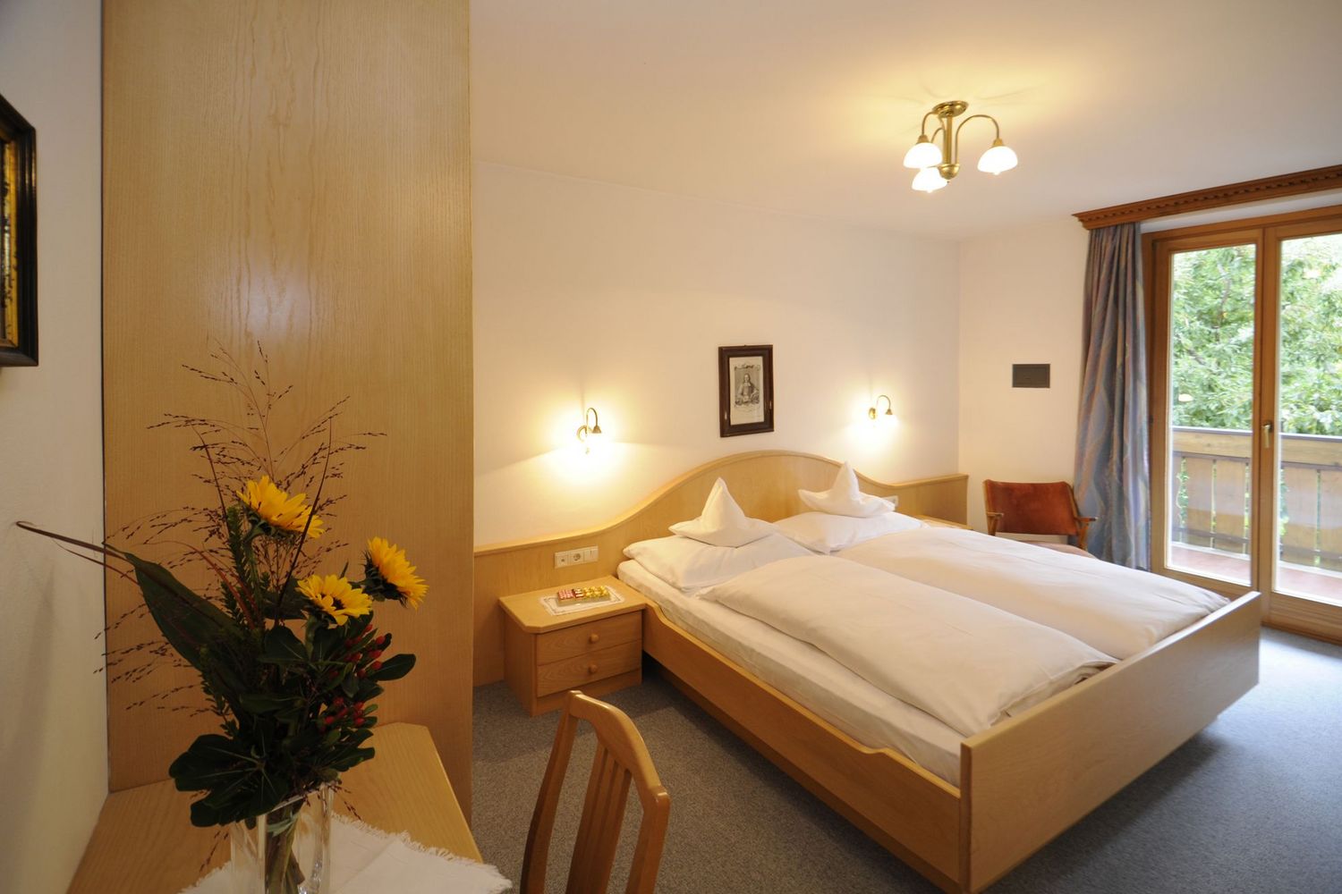 Gemütliches Schlafzimmer mit Doppelbett, Holzmöbeln und Balkon mit Blick ins Grüne