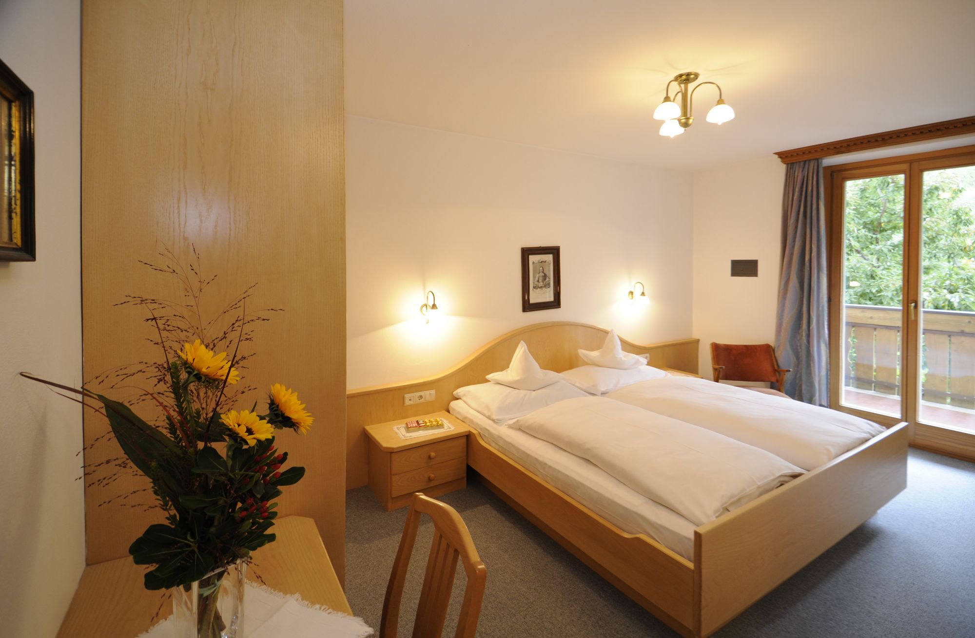 Gemütliches Hotelzimmer mit Doppelbett, Holzmöbeln und Balkonblick