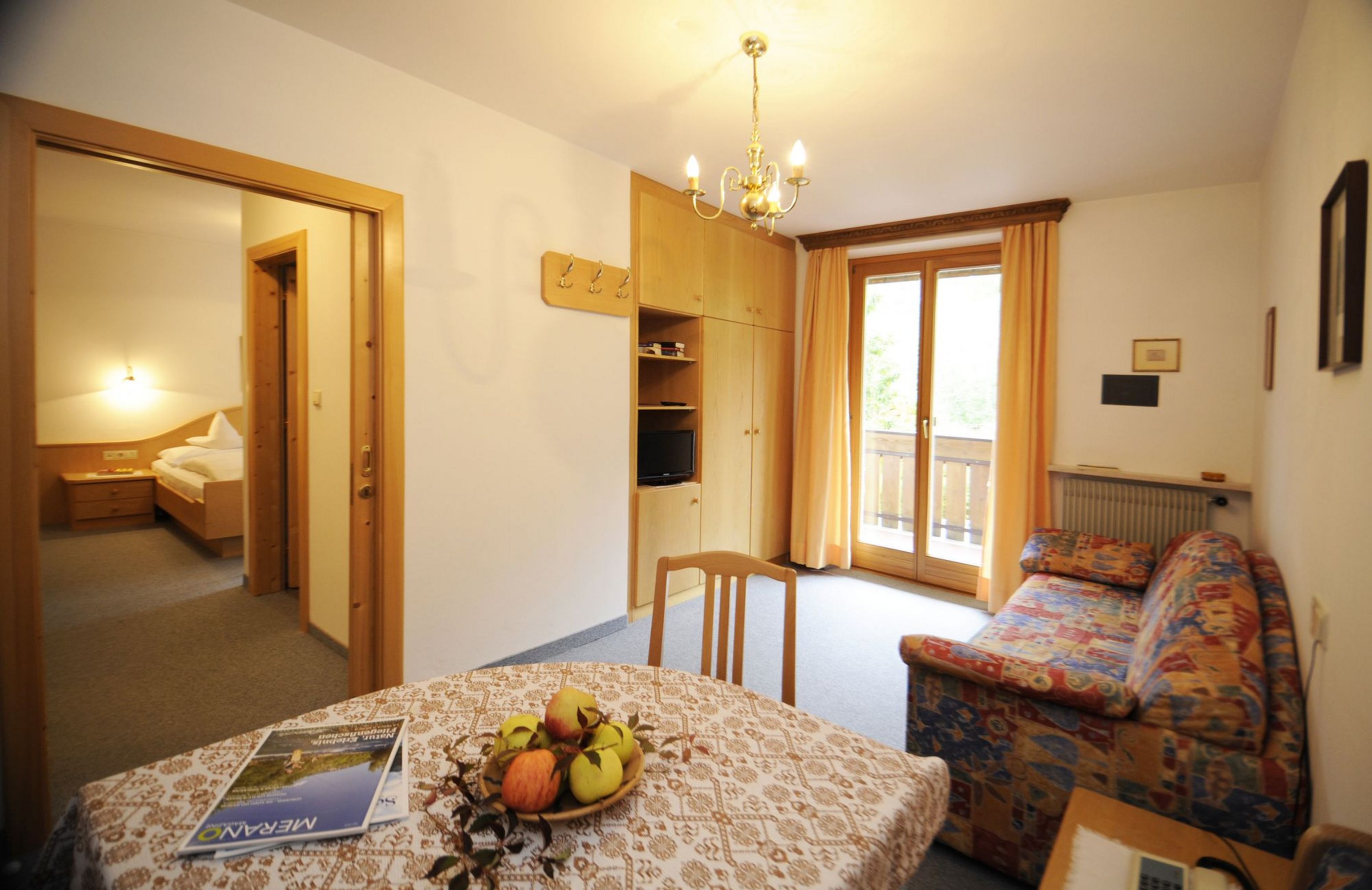 Gemütliches Wohnzimmer mit Sofa, Tisch und Blick in ein Schlafzimmer