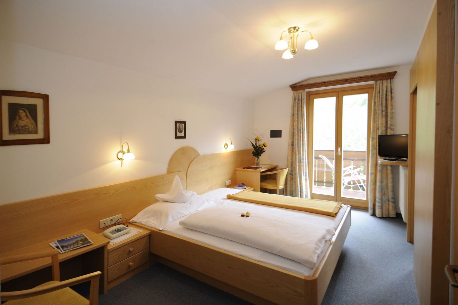 Hell eingerichtetes Hotelzimmer mit Holzmöbeln und Balkonzugang