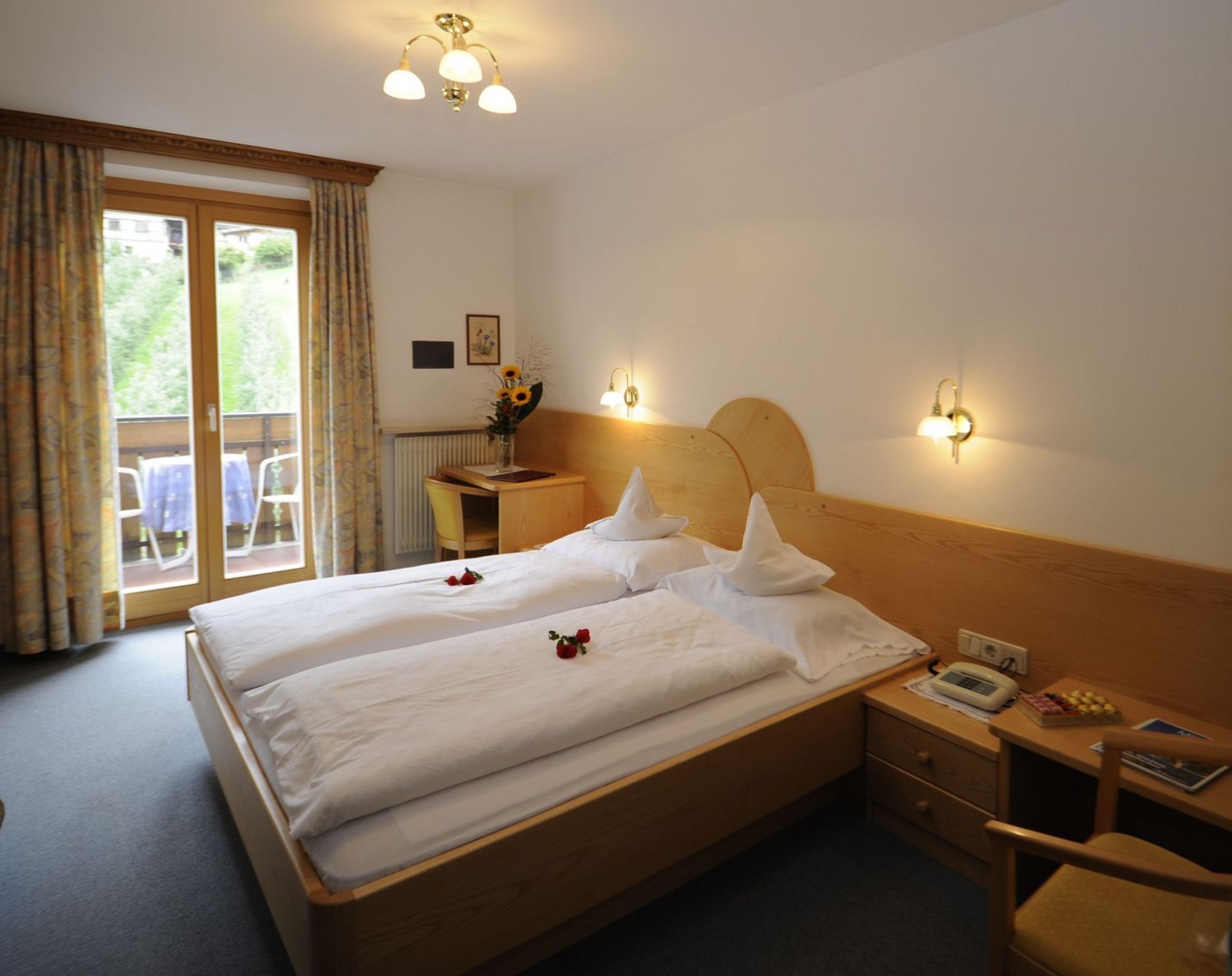 Gemütliches Hotelzimmer mit zwei Einzelbetten, gläserner Balkontür und Holzmöbeln