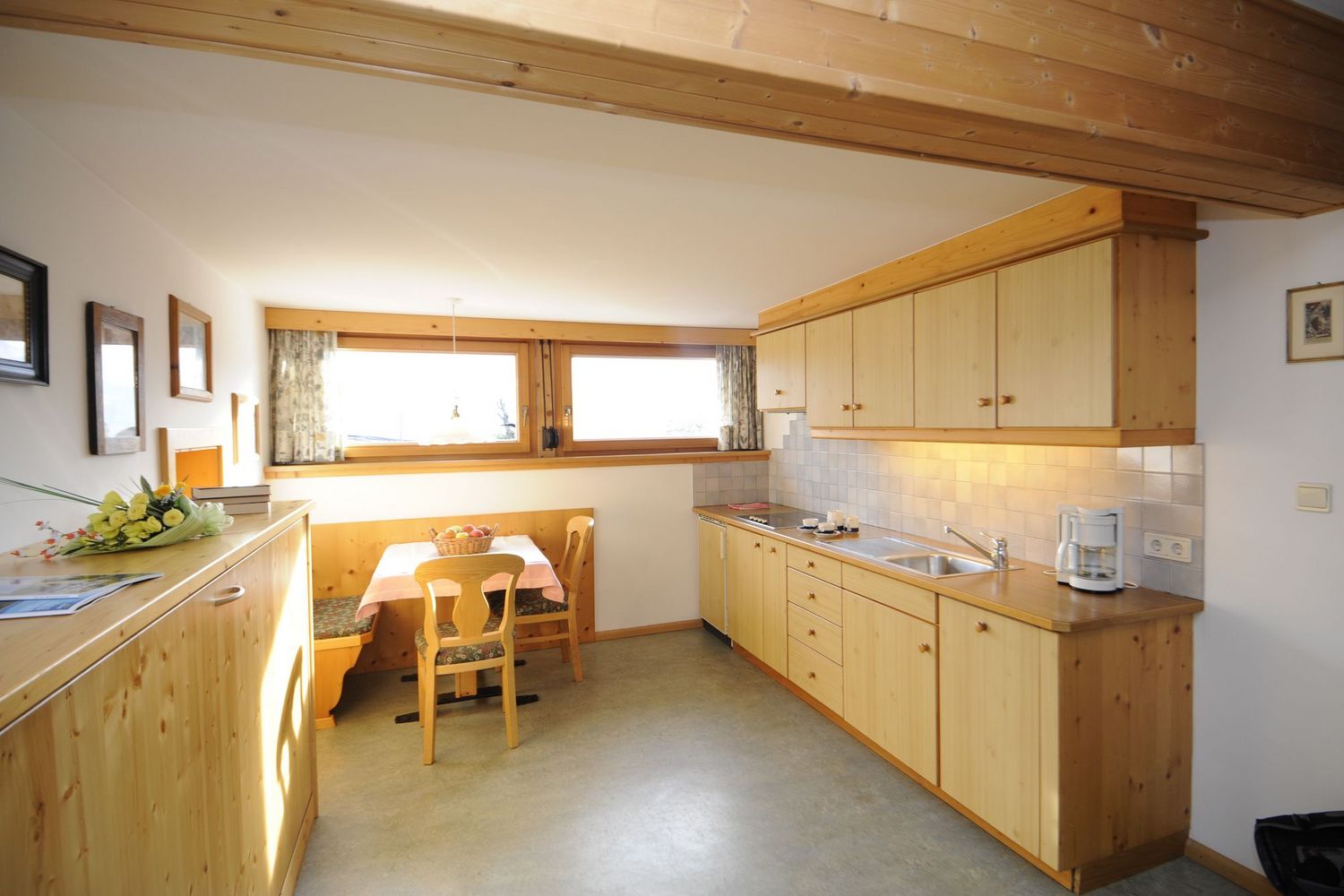 Helle Küche mit Holzmöbeln und Essecke am Fenster